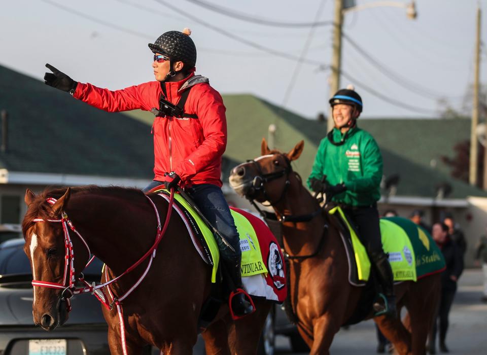 Assistant trainer Takahide Ando for Kentucky Derby contender Continuar, foreground, points towards the quarantine barn assistant trainer Masanari Tanaka smiles aboard Derma Sotogake  after a workout at the track April 25, 2023 at Churchill Downs in Louisville, Ky.