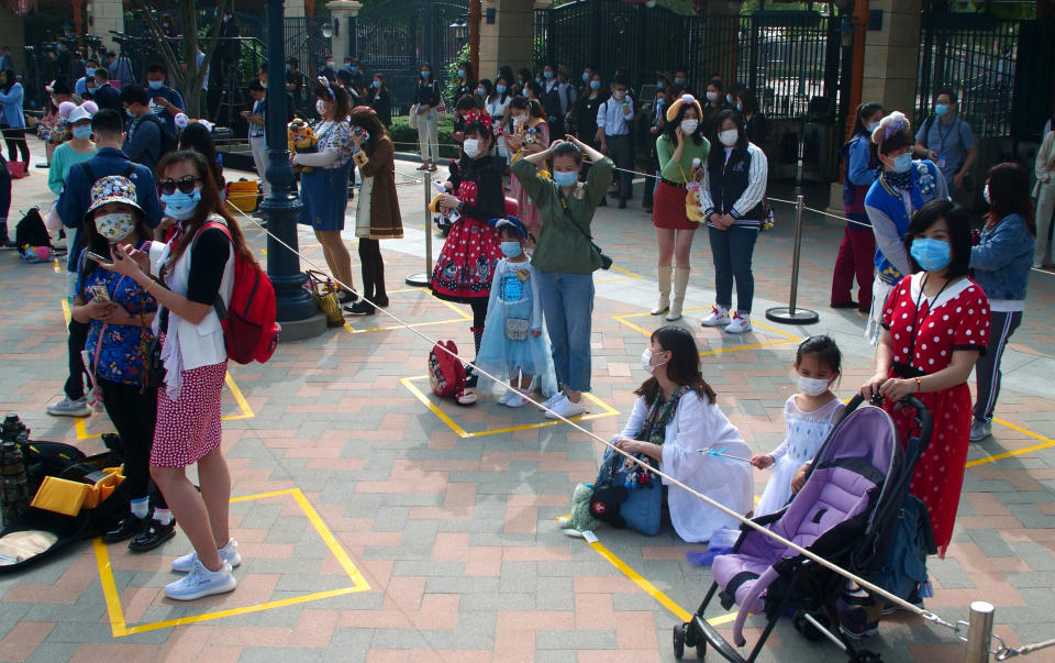 Visitors, wearing face masks, wait to enter the Disneyland theme park in Shanghai as it reopened, Monday, May 11, 2020. Visits will be limited initially and must be booked in advance, and the company said it will increase cleaning and require social distancing in lines for the various attractions. With warmer weather and new coronavirus cases and deaths falling to near-zero, China has been reopening tourist sites such as the Great Wall and the Forbidden City palace complex in Beijing. (AP Photo/Sam McNeil)