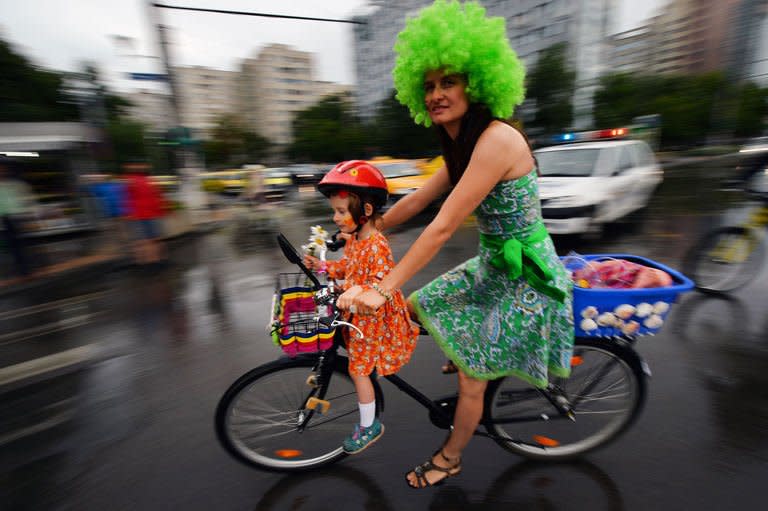 A woman rides a bike with her daughter during the third "SkirtBike" in Bucharest on June 2, 2013. More than 1,500 Romanian women in colourful skirts and high heels cycled through the country's main cities to promote urban biking as a "stylish and fun" way of transport