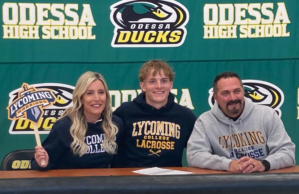 Odessa senior Braden Hill (center), who plans to play lacrosse at Lycoming College, is supported by his mother, Kim, and father, Jeff, at the high school’s first athletic signing ceremony on Thursday.