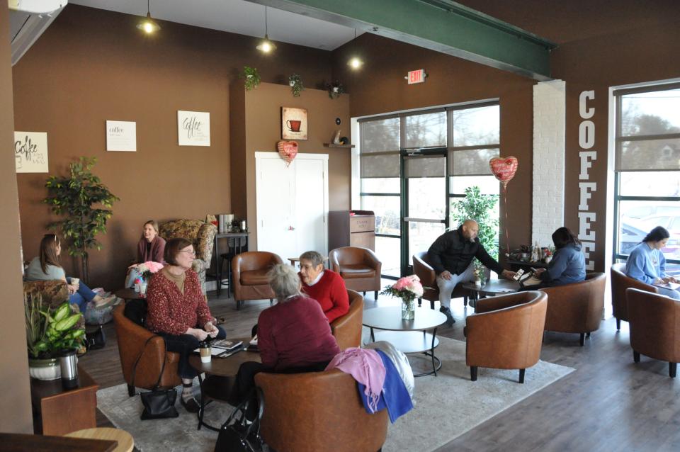 Customers sip, eat and talk in the dining area at the Corner Grounds Café in Odessa Feb. 15, 2024. The coffee shop is in a building that was a gas station. The large windows at right are where the garage doors were for the car repair service bays.