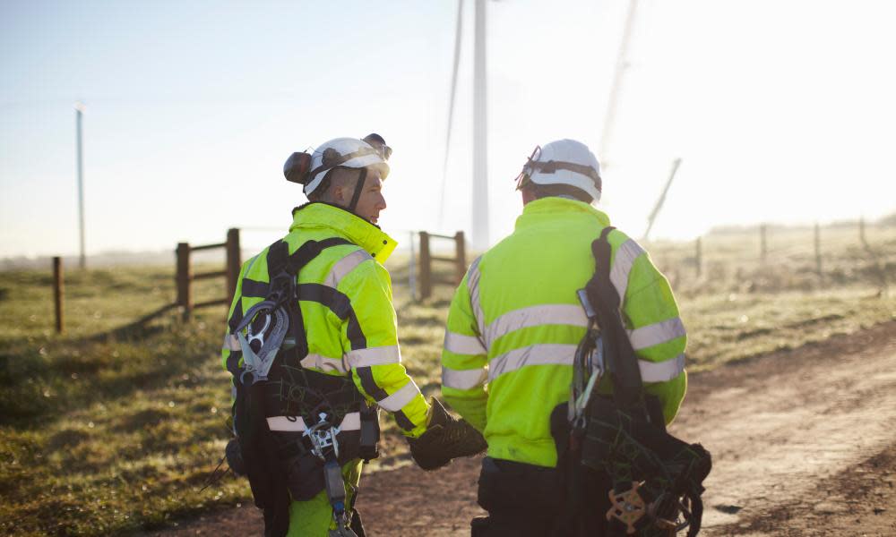 Two engineers at wind farm, walking together, rear view