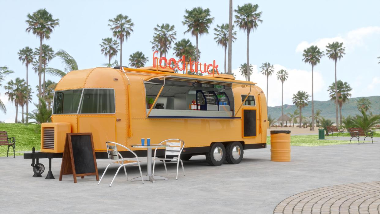 Food truck on wheels in a park.