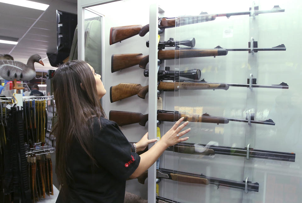 FILE - In this Wednesday, Oct. 4, 2017 file photo, a salesperson checks rifles in a gun shop display in Sydney, Australia. A documentary aired in March 2019 by Al Jazeera reported officials with Australia's far-right One Nation party met with two National Rifle Association representatives and other gun-rights advocates seeking money to undermine Australian gun laws. (AP Photo/Rick Rycroft)