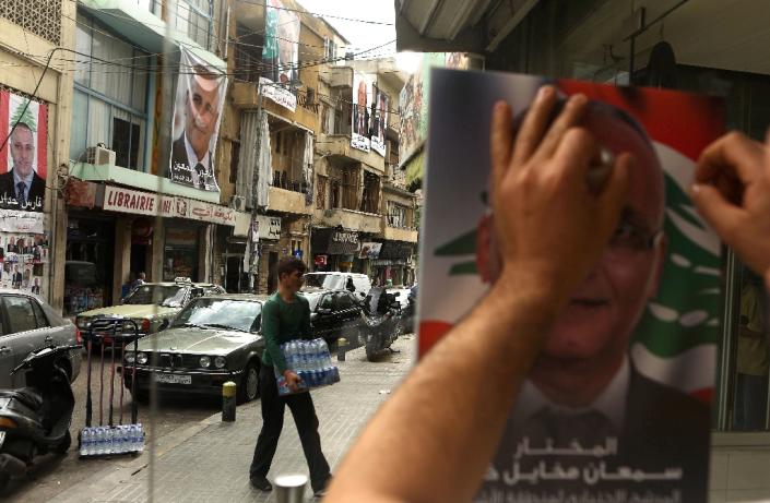 A Lebanese man puts up a poster of a candidate in the Beirut municipal elections (AFP Photo/Patrick Baz)