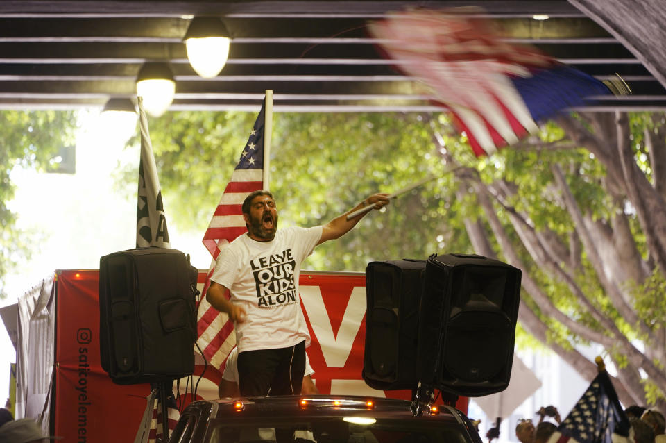 A member of the Parents Rights group rides on top of a truck along Third St., downtown to Los Angeles Unified School District headquarters on Tuesday, Aug. 22, 2023, in Los Angeles. (AP Photo/Damian Dovarganes)