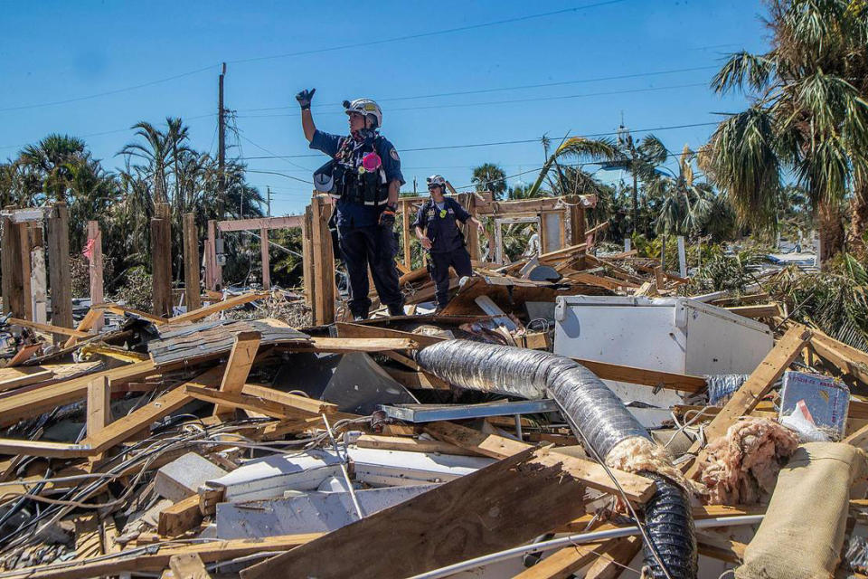 A member of a search and rescue team confirms to teammates the discovery of a body in Fort Myers Beach, Fla., on Sept. 30, two days after Hurricane Ian hit Florida's west coast. (El Nuevo Herald / via Getty Images)