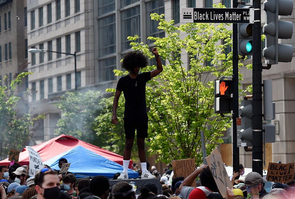A demonstrator holds up his fist near a street sign that has been renamed "Black Lives Matter Plaza" near the White House during a peaceful protest against police brutality and racism, on June 6, 2020 in Washington, D.C.