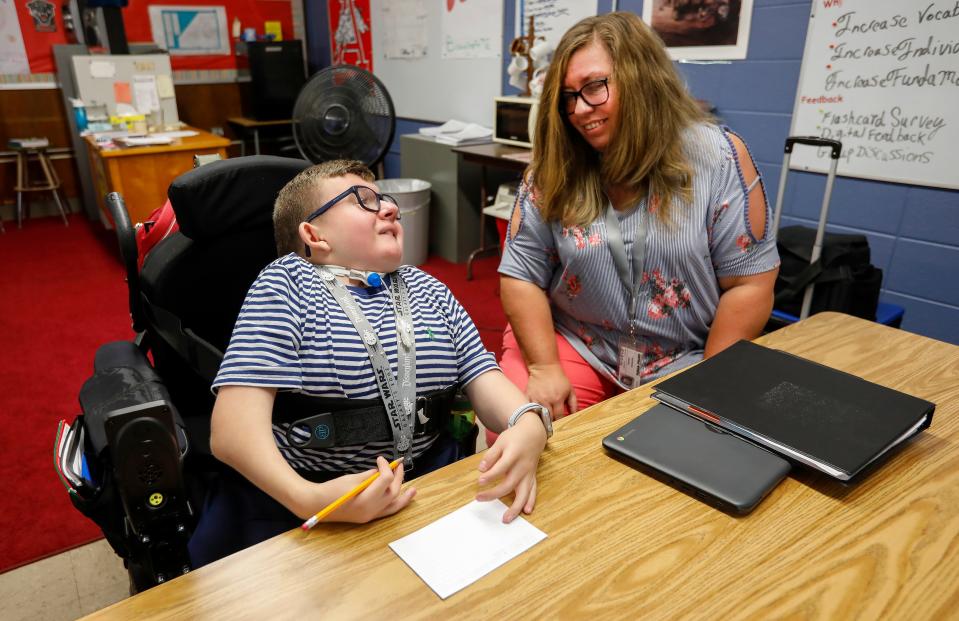 In a photo from 2019, Collin Langston, then a freshman at Glendale High School, smiles along with his nurse Nikki Dugger as he shows her his idea for a writing assignment.