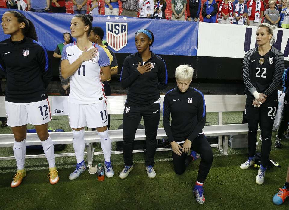 FILE - USA's Megan Rapinoe kneels next to teammates Christen Press (12), Ali Krieger (11), Crystal Dunn (16) and Ashlyn Harris (22) as the U.S. national anthem is played before an exhibition soccer match against Netherlands Sunday, Sept. 18, 2016, in Atlanta. Rapinoe knelt during the national anthem in solidarity with Colin Kaepernick, the former San Francisco 49ers quarterback who knelt during the anthem to call attention to racial inequality.(AP Photo/John Bazemore, File)