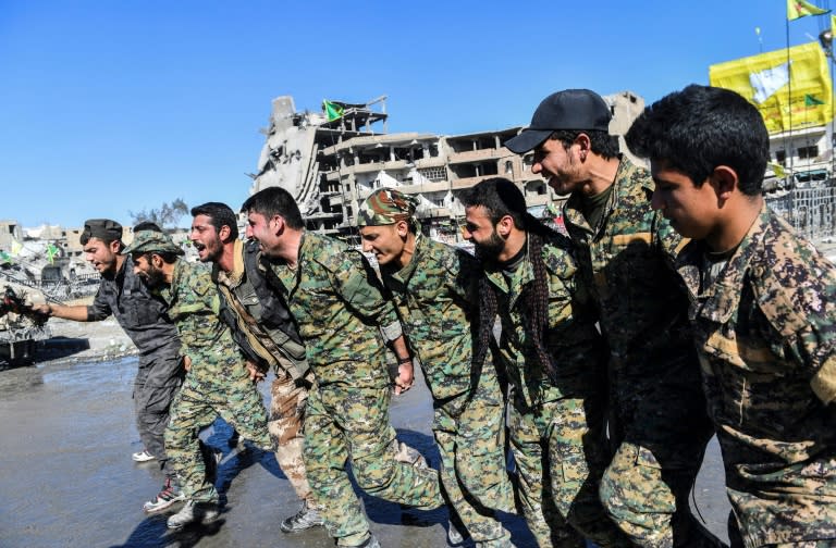 Members of the Syrian Democratic Forces (SDF) celebrate on the iconic Al-Naim square in Raqa on October 18, 2017, after retaking the city from Islamic State group