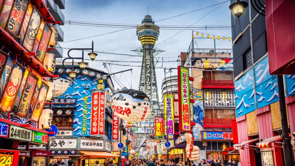 Osaka Tower and view of the neon advertisements in Shinsekai district at dusk, Osaka, Japan