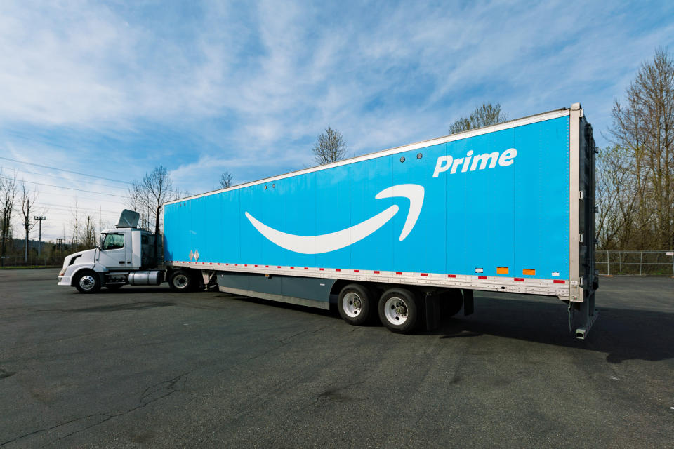 An truck with the Amazon Prime logo against a blue background on the trailer.