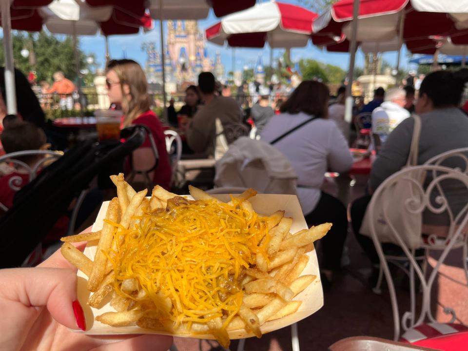 hand holding fast-food boat of chili-cheese fries from casey's corner at magic kingdom