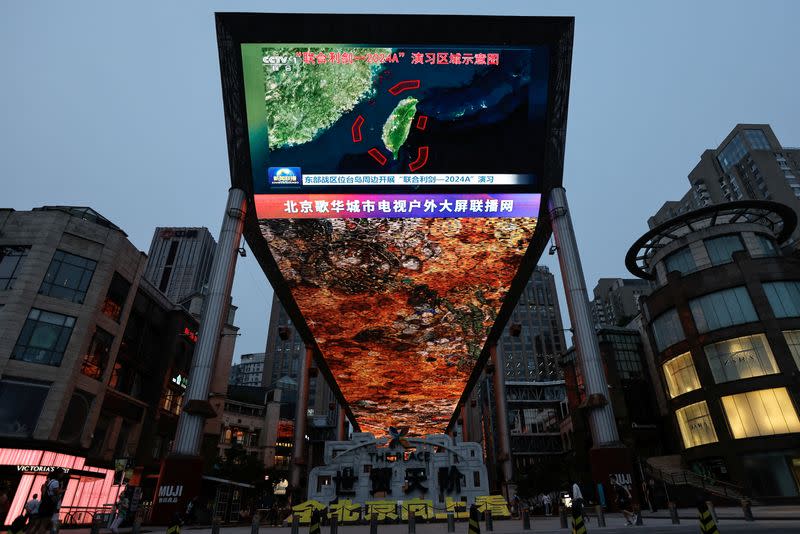 FILE PHOTO: A large screen shows news footage of a map of military drills around Taiwan conducted by the Eastern Theatre Command of the PLA, in Beijing