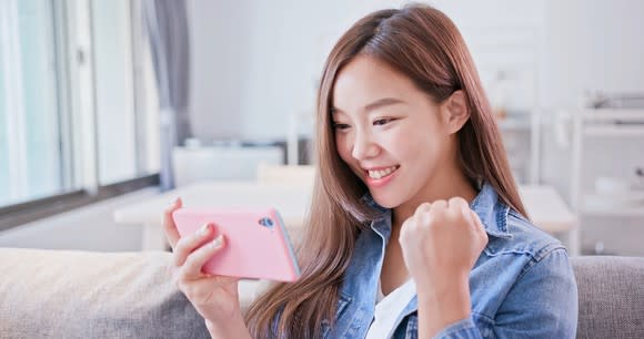 A young woman smiling while looking at her mobile phone