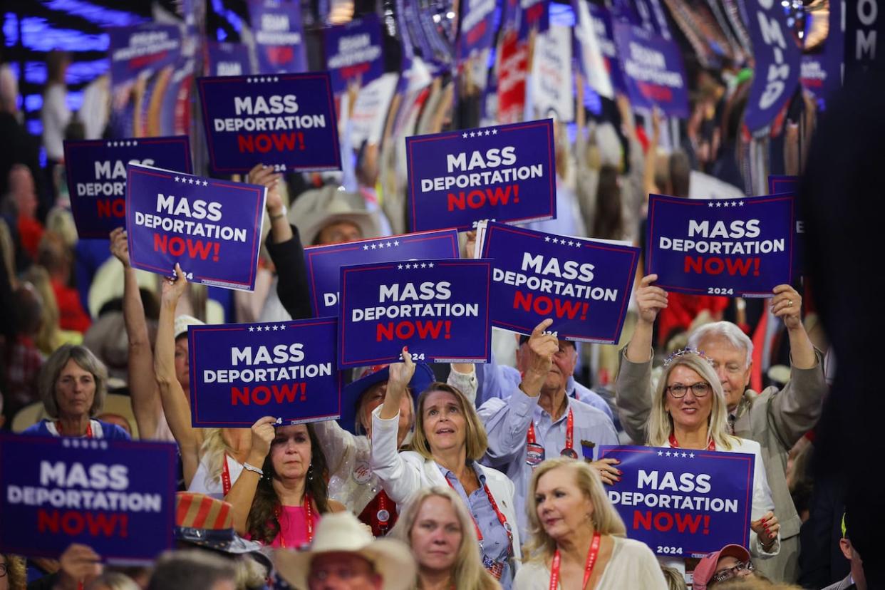 People at the Republican National Convention wave 'Mass Deportation Now!' signs, a reference to presidential candidate Donald Trump's proposal to deport millions of migrants. (Brian Snyder/Reuters - image credit)