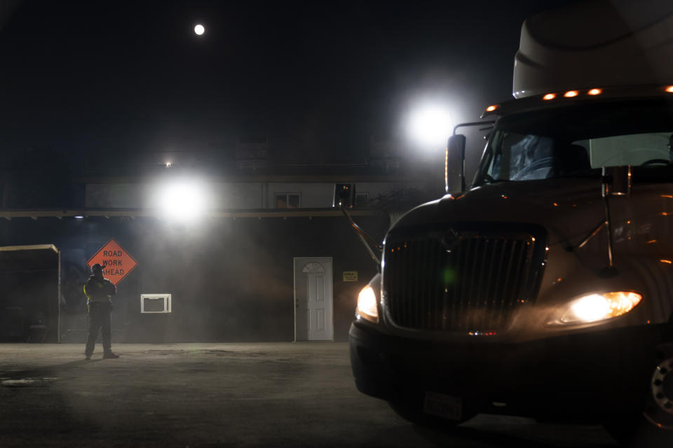 Evening class instructor Pavel Cruz, left, stands in a dusty lot as his student practices steering a truck at California Truck Driving Academy in Inglewood, Calif., Wednesday, Nov. 17, 2021. Business is booming at a truck-driving academy in suburban Los Angeles amid a nationwide shortage of long-haul drivers. The California Truck Driving Academy in Inglewood has seen annual enrollment grow by almost 20% since last year. (AP Photo/Jae C. Hong)