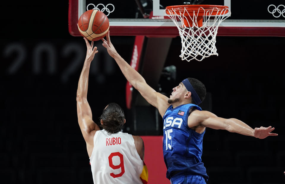 United States' Devin Booker (15), right, tries to block a shot by Spain's Ricky Rubio (9) during men's basketball quarterfinal game at the 2020 Summer Olympics, Tuesday, Aug. 3, 2021, in Saitama, Japan. (AP Photo/Charlie Neibergall)