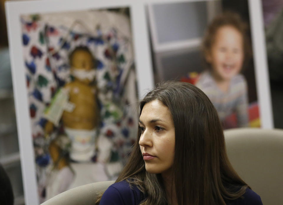 Alyssa Hernandez listens as opponents to a proposal to give state public health officials instead of local doctors the power to decide which children can skip their shots before attending school, speak at the Capitol Wednesday, April 24, 2019, in Sacramento, Calif. Hernandez, whose son Noah, seen in photos in the background, received a liver transplant when he was six months old and cannot be vaccinated against many vaccine-preventable diseases, spoke in support of the bill. (AP Photo/Rich Pedroncelli)
