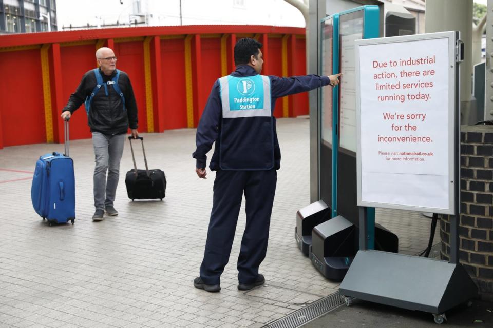 A station worker assists a passenger at Paddington station (Ashlee Ruggels/PA) (PA Wire)