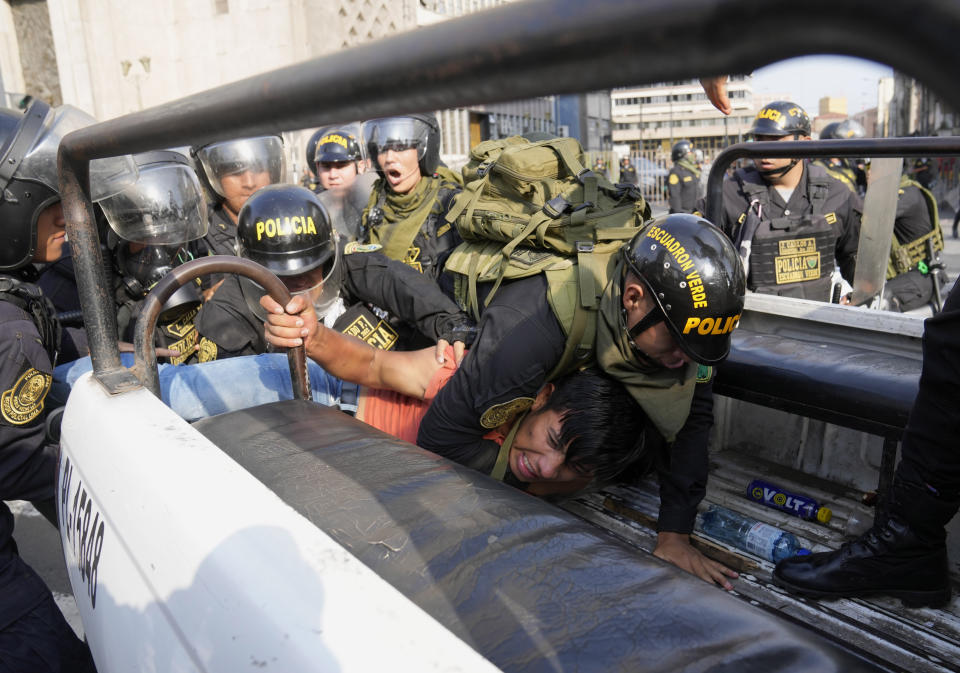 An anti-government protesters who traveled to the capital from across the country to march against Peruvian President Dina Boluarte, is detained and thrown on the back of police vehicle during clashes in Lima, Peru, Thursday, Jan. 19, 2023. Protesters are seeking immediate elections, Boluarte's resignation, the release of ousted President Pedro Castillo and justice for up to 48 protesters killed in clashes with police. (AP Photo/Martin Mejia)