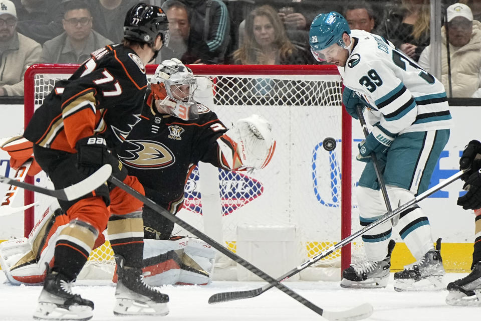 San Jose Sharks center Logan Couture, right, tries to redirect a shot as Anaheim Ducks right wing Frank Vatrano, left, and goaltender John Gibson defend during the first period of an NHL hockey game Wednesday, Jan. 31, 2024, in Anaheim, Calif. (AP Photo/Mark J. Terrill)