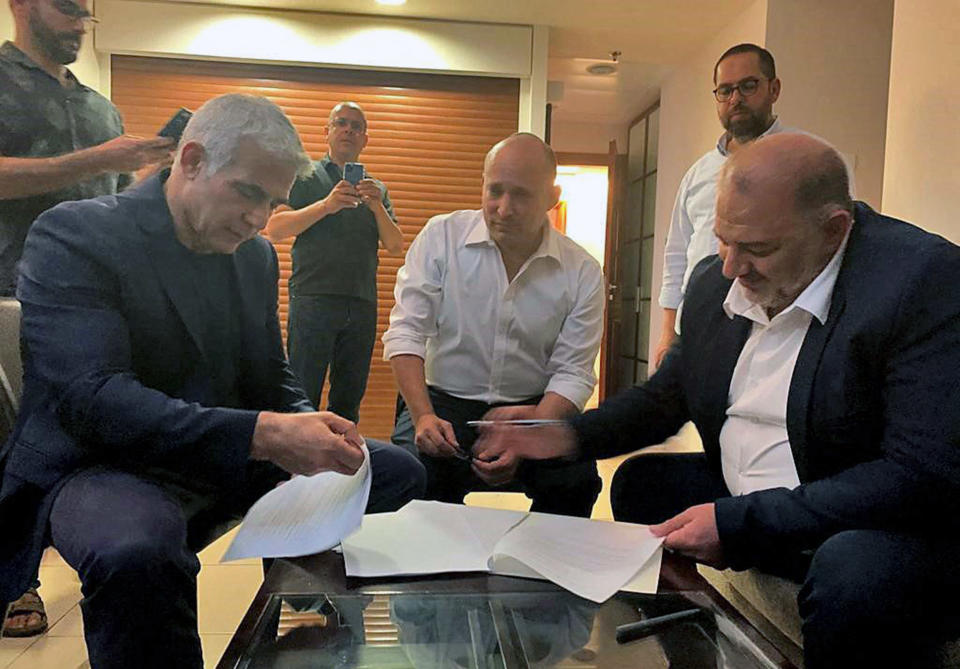 Image: Mansour Abbas, Yair Lapid and Naftali Bennett signing a coalition agreement. (United Arab List Raam / AFP - Getty Images)