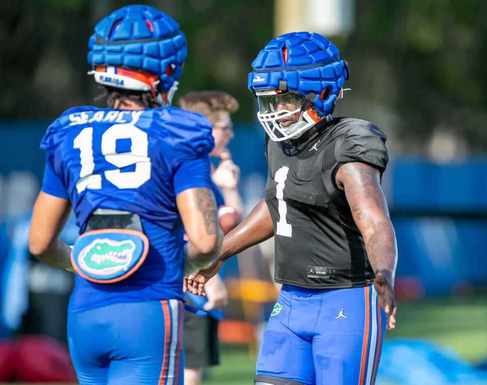 Florida defensive lineman Justus Boone (1) tags Florida edge rusher T.J. Searcy (19) as they run a drill during Florida spring football practice at Sanders Practice Fields on Tuesday.