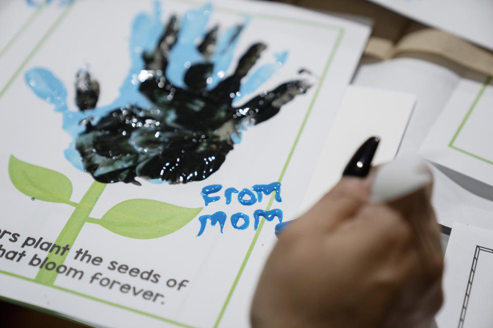 Raquel Ayala signs a handprint of paint for her daughter Crystal Martinez during a special visit at Logan Correctional Center, Saturday, May 20, 2023, in Lincoln, Illinois. Rare programs like the Reunification Ride, a donation-dependent initiative that buses prisoners' family members from Chicago to Illinois' largest women's prison every month so they can spend time with their mothers and grandmothers, are a crucial lifeline for families, prisoners say. (AP Photo/Erin Hooley)