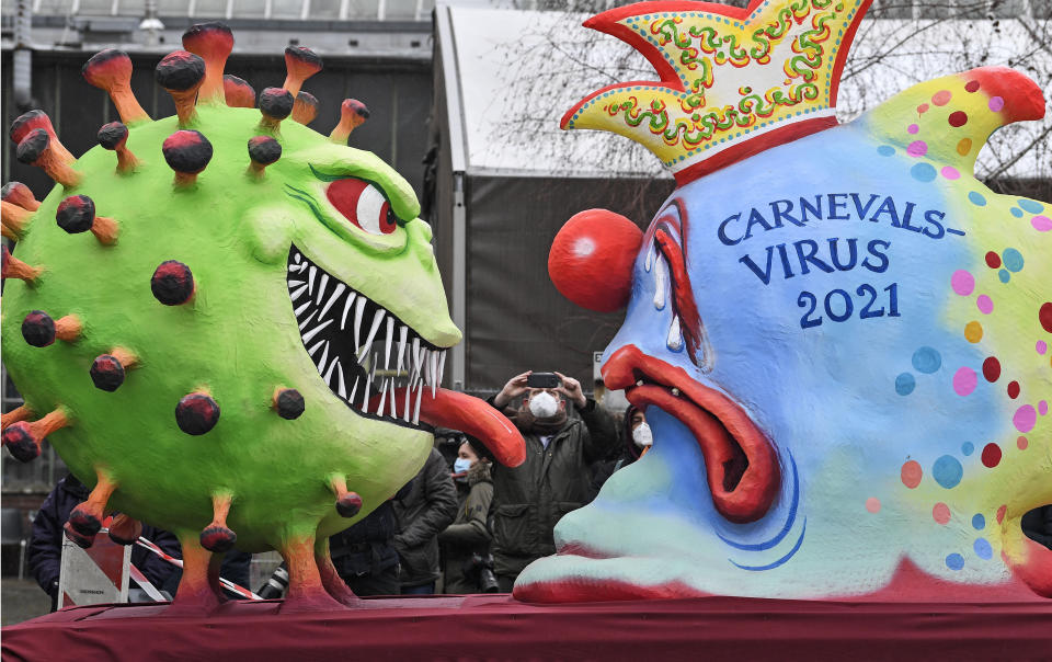 A political carnival float depicting the coronavirus vs the carnival virus is rolled out to be shown in the streets when the traditional carnival parade was canceled due to the coronavirus pandemic in Duesseldorf, Germany, Monday, Feb. 15, 2021. Eight floats are pulled through the empty streets in Duesseldorf, where normally hundreds of thousands of people would celebrate the street carnival. (AP Photo/Martin Meissner)