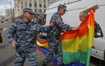 FILE - Russian police officers detain a gay rights activist with his flag during an attempt to hold a gay pride parade in Moscow, Russia, Sunday, May 27, 2012. Russia passed a law in 2013 that bans the depiction of homosexuality to minors, something human rights groups views as a way to demonize LGBT people and discriminate against them. (AP Photo/Mikhail Metzel, File)