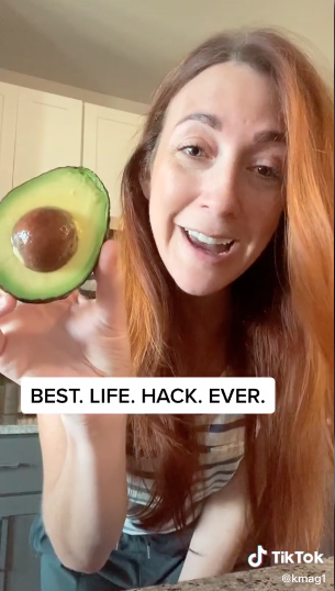 woman holding up half an avocado