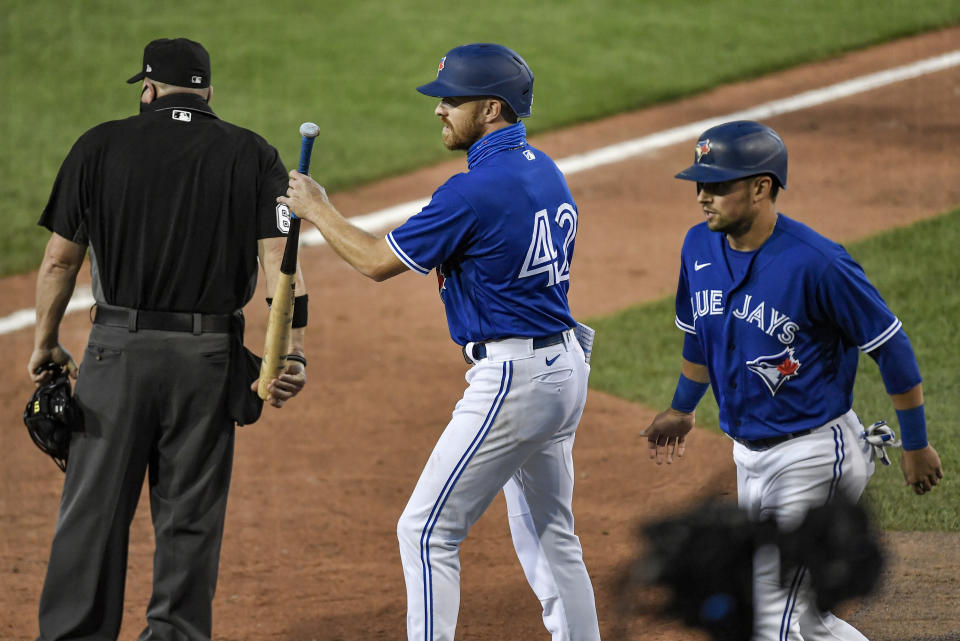 Toronto Blue Jays' Derek Fisher, center, takes a bat from the umpire after he and Joe Panik, right, scored against the Baltimore Orioles on a single by Cavan Biggio during the fourth inning a baseball game in Buffalo, N.Y., Saturday, Aug. 29, 2020. (AP Photo/Adrian Kraus)