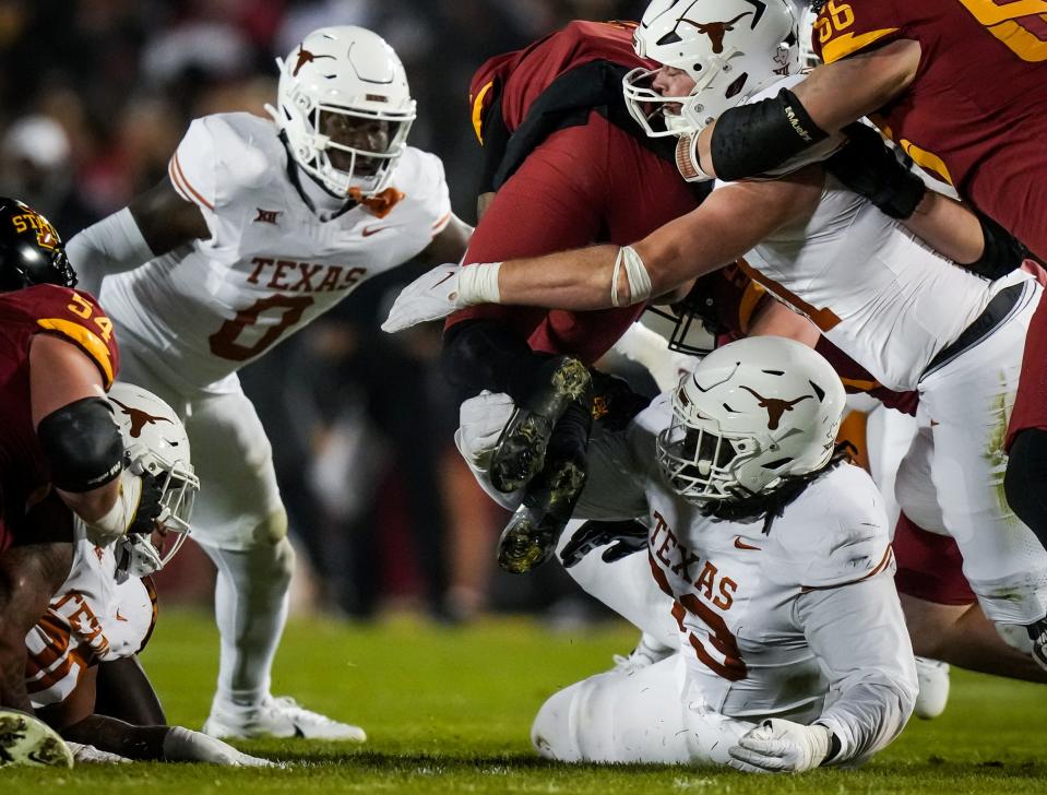 Texas tacke T'Vondre Sweat, on the ground, and teammate Anthony Hill Jr., left, combined with another teammate to tackle an Iowa State player during Saturday's win. The Horns can advance to the Big 12 title game with a win at home Friday against Texas Tech.