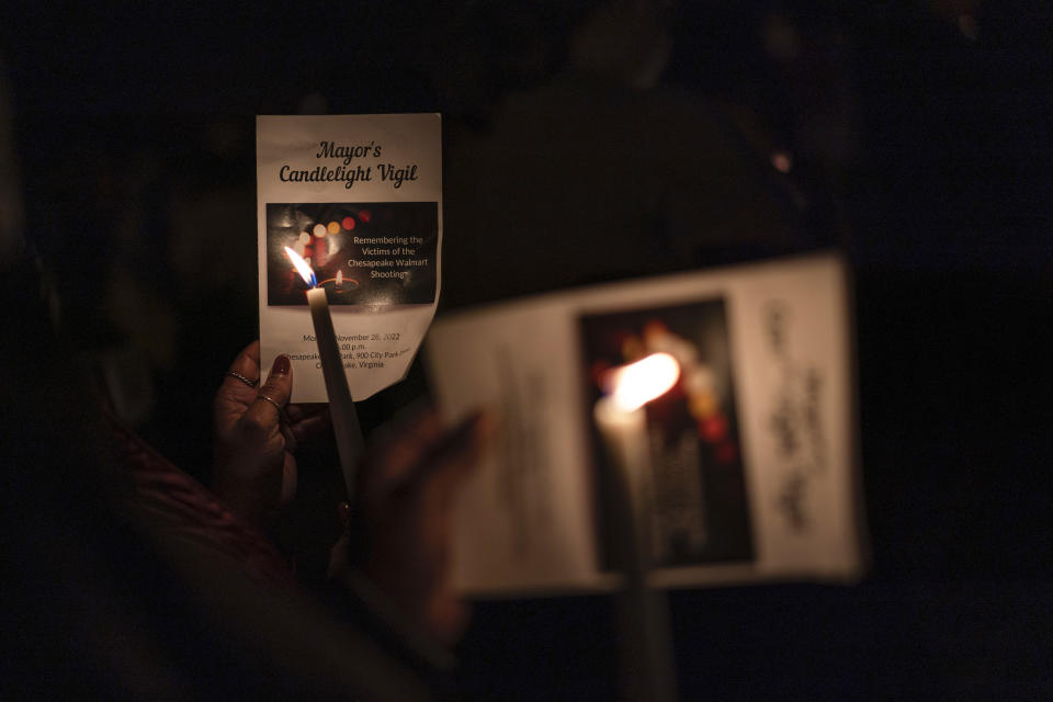 People use programs to shield their candles from the wind during a candlelight vigil at Chesapeake City Park in Chesapeake, Va., Monday, Nov. 28, 2022, for the six people killed at a Walmart in Chesapeake, Va., when a manager opened fire with a handgun before an employee meeting last week. (AP Photo/Carolyn Kaster)