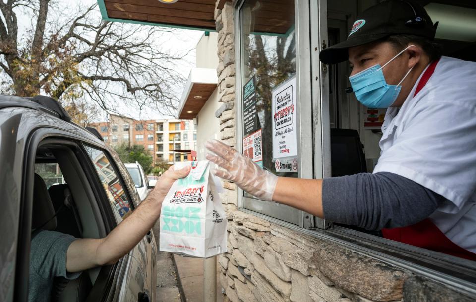 P. Terry's Burger Stand's Erika Garibay waves to a customer after passing the person a meal during the annual P. Terry's Burger Stand's Giving Back Day for Season for Caring last year. This year, the Giving Back Day will be Saturday.