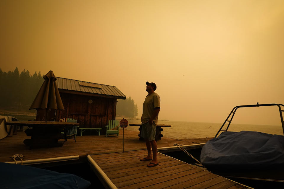 A business owner, who declined to give his name, looks up at the smoke-covered sky from the Creek Fire at his boat rental place Sunday, Sept. 6, 2020, in Shaver Lake, Calif. (AP Photo/Marcio Jose Sanchez)