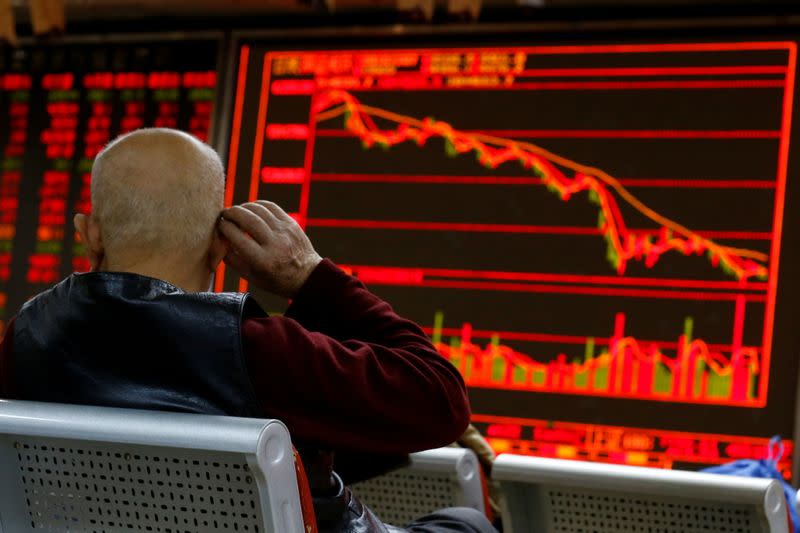 FILE PHOTO: An investor sits in front of a board showing stock information at a brokerage office in Beijing