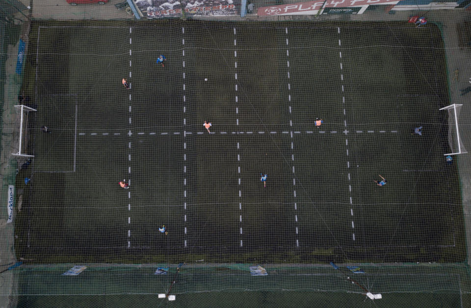 Men play soccer at a local club, Play Futbol 5, in Pergamino, Argentina, Wednesday, July 1, 2020. In order to continue playing amid government restrictions to curb the spread of the new coronavirus, the club divided its soccer field into 12 rectangles to mark limited areas for each player, keeping them from making physical contact. (AP Photo/Natacha Pisarenko)