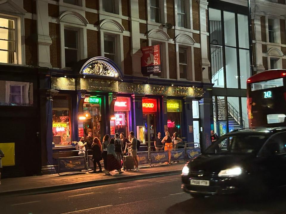 shot of a bar at night in shoreditch london with cars passing by in front