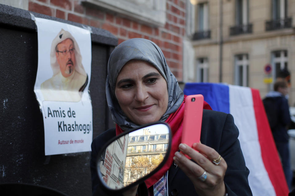 Activist Magda Mahfouz takes a selfie next to a portrait reading "Friends of Khashoggi around the world" during a protest closed to the Saudi Arabia embassy, in Paris, Thursday, Oct. 25, 2018. Saudi prosecutors say the killing of journalist Jamal Khashoggi was planned, state-run media reported Thursday, reflecting yet another change in the shifting Saudi Arabian account of what happened to the writer who was killed by Saudi officials in their Istanbul consulate. (AP Photo/Francois Mori)