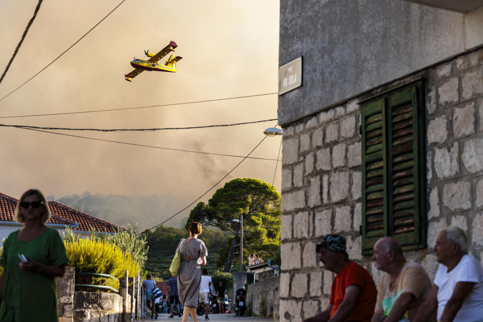 A firefighting plane sprays water to extinguish wildfire at Ciovo island, Croatia, Thursday, July 27, 2023. A large fire is reported on island of Ciovo, close to Split on the Croatian Adriatic coast. (AP Photo/Miroslav Lelas)