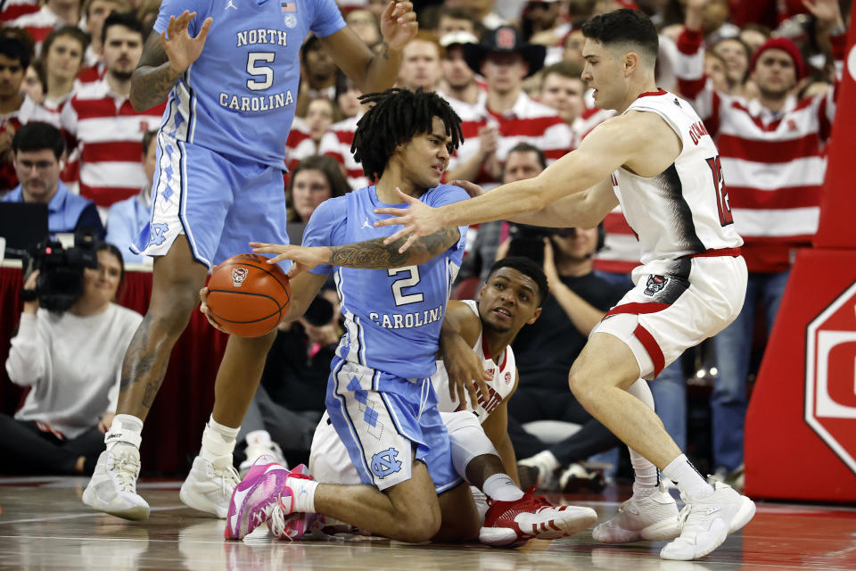 North Carolina's Elliot Cadeau (2) struggles to maintain control of the ball with North Carolina State's Casey Morsell, center, and Michael O'Connell (12) during the second half of an NCAA college basketball game in Raleigh, N.C., Wednesday, Jan. 10, 2024. (AP Photo/Karl B DeBlaker)