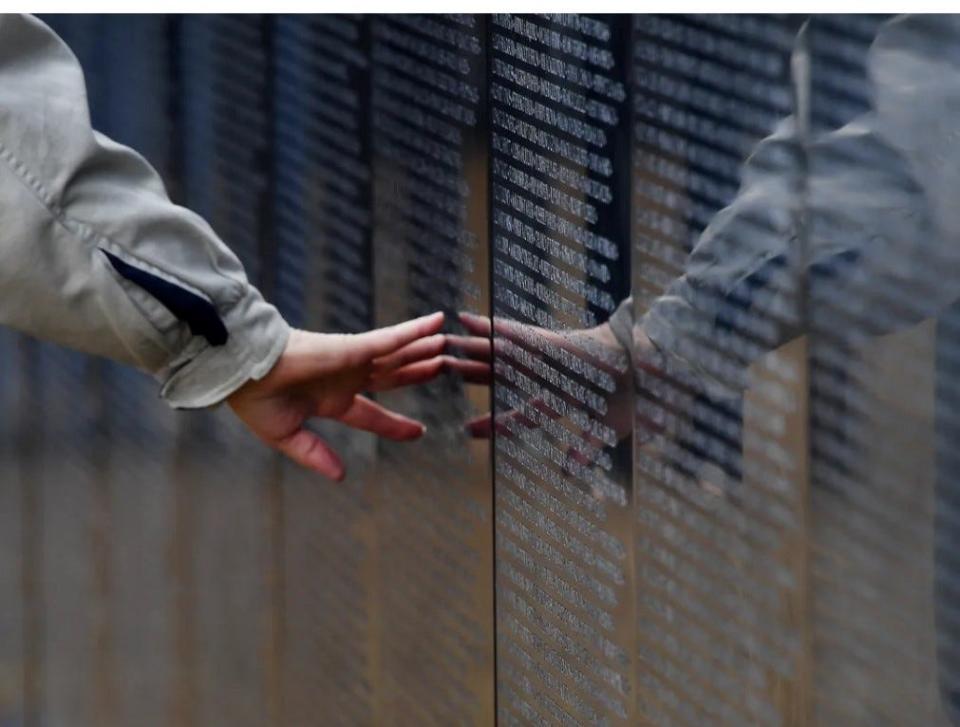 A hand gliding across the names of the fallen Vietnam Soldiers of the Wall That Heals.