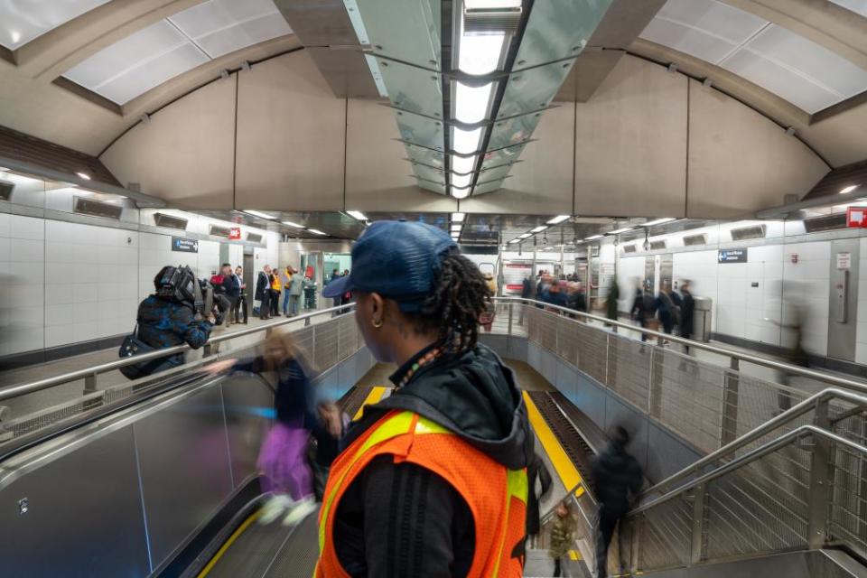 A transportation worker sprays disinfectant and wipes an escalator handrail at the 86th Street subway station in New York