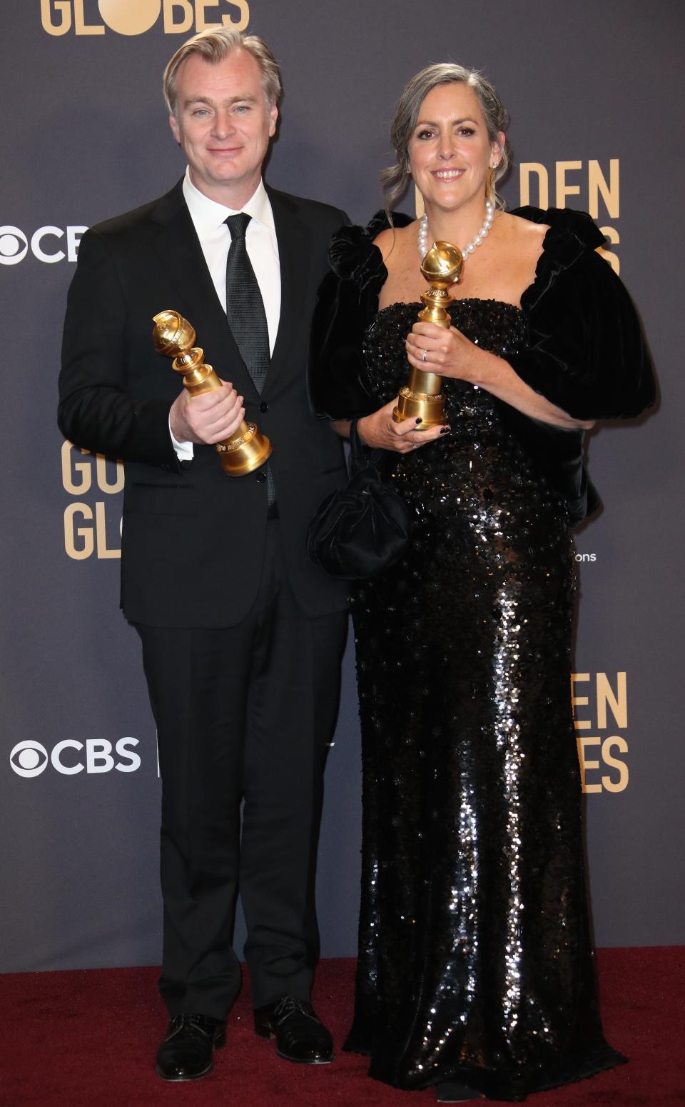 "Oppenheimer" producers Christopher Nolan, left, and Emma Thomas pose with their Golden Globes.
