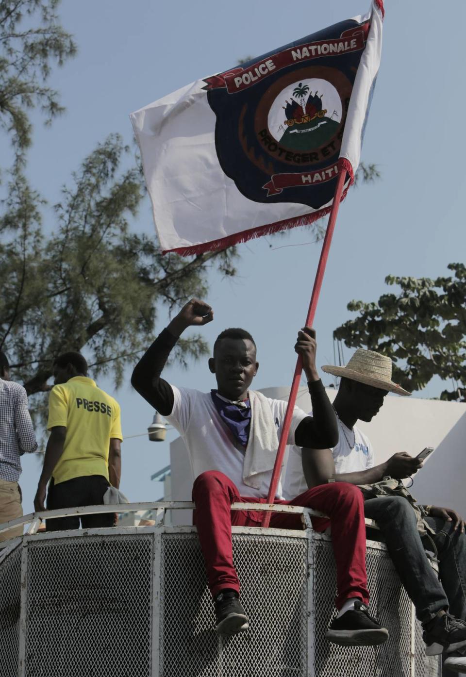 A young protester holds the banner of the Haiti National Police during a Nov. 17, 2019 protest where officers took to the streets demanding better working conditions and a union to protect their rights.