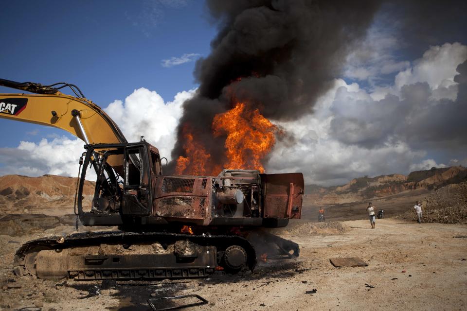 A backhoe used for illegal mining burns after being destroyed by authorites in Huepetuhe district in Peru's Madre de Dios region in Peru, Monday, April 28, 2014. Authorities began enforcing a ban on illegal mining Monday in the Huepetuhe district. They had given the state’s thousands of illegal miners until April 19 to get legal or halt operations. (AP Photo/Rodrigo Abd)