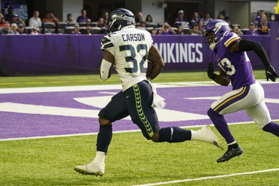 Seattle Seahawks running back Chris Carson (32) heads to the end zone for a touchdown past Minnesota Vikings free safety Xavier Woods (23) in the first half of an NFL football game in Minneapolis, Sunday, Sept. 26, 2021. (AP Photo/Jim Mone)